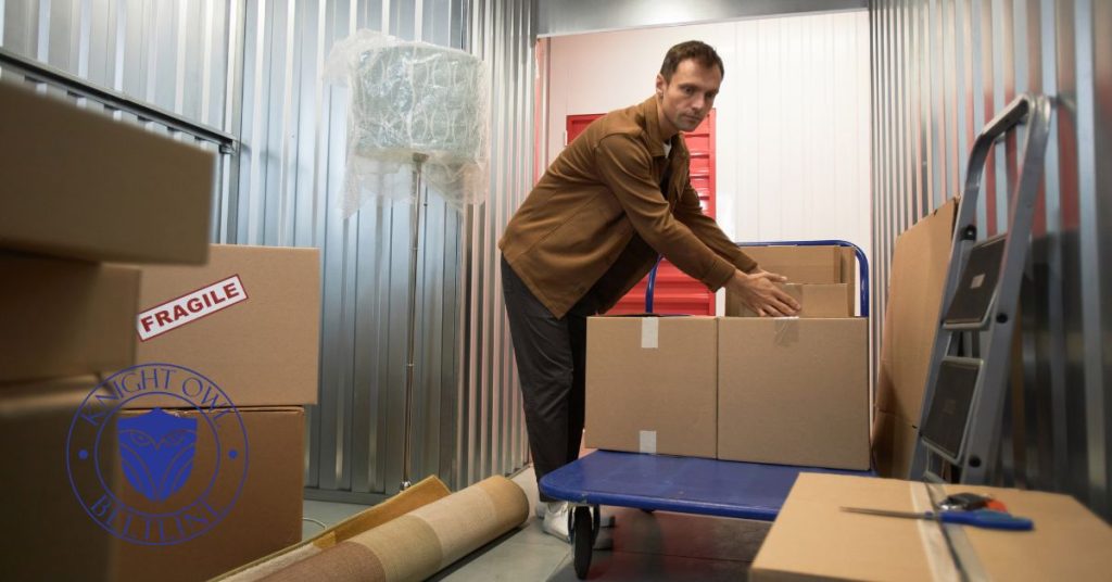 A man loading cardboard boxes onto a blue moving flatbed dolly inside a clean storage unit rental at Knight Owl Storage on Beltline in Mobile AL