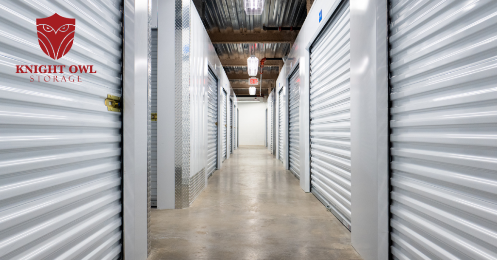 A brightly lit hallway of clean indoor climate controlled storage units with white corrugated roll up doors and polished concrete floors.